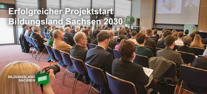Das Foto zeigt die Auftaktveranstaltung zum »Bildungsland 2030«. Zu sehen sind Sitzreihen von hinten. Das Foto hat die Aufschrift »*Erfolgreicher Projektstart Bildungsland Sachsen 2030«.